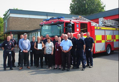 health and safety team in front of fire engine with award
