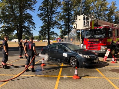 firefighters washing a car with a fire engine behind it
