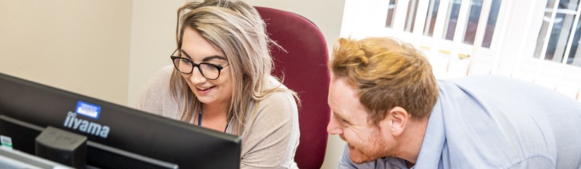 Two support staff at a computer