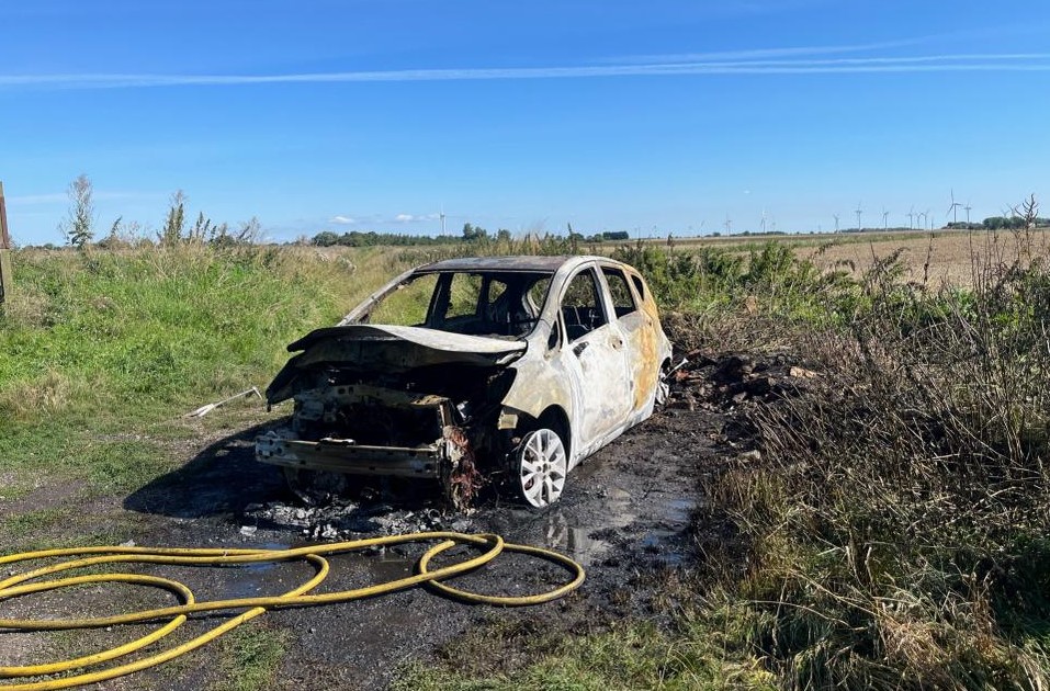 Car and surrounding area damaged by fire.