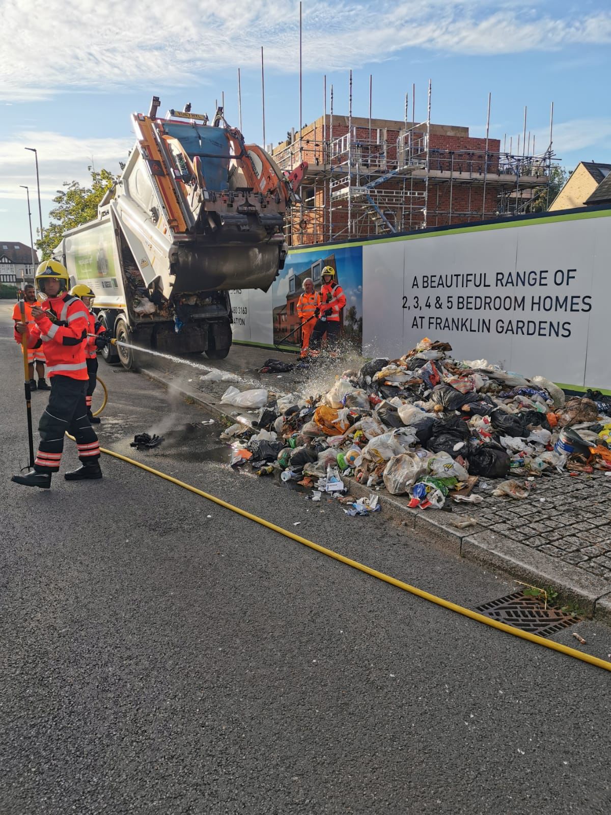 Firefighters tackling a fire involving refuse from a bin lorry.