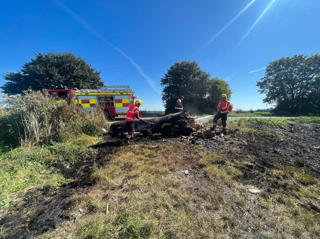 Firefighters tackling a log fire.